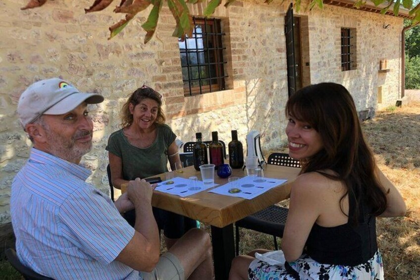 Three people sitting at an outdoor table with wine bottles and glasses. 5