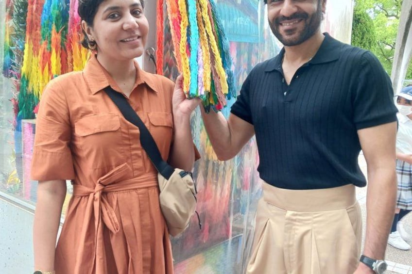 Two people standing in front of a colorful mural. 4