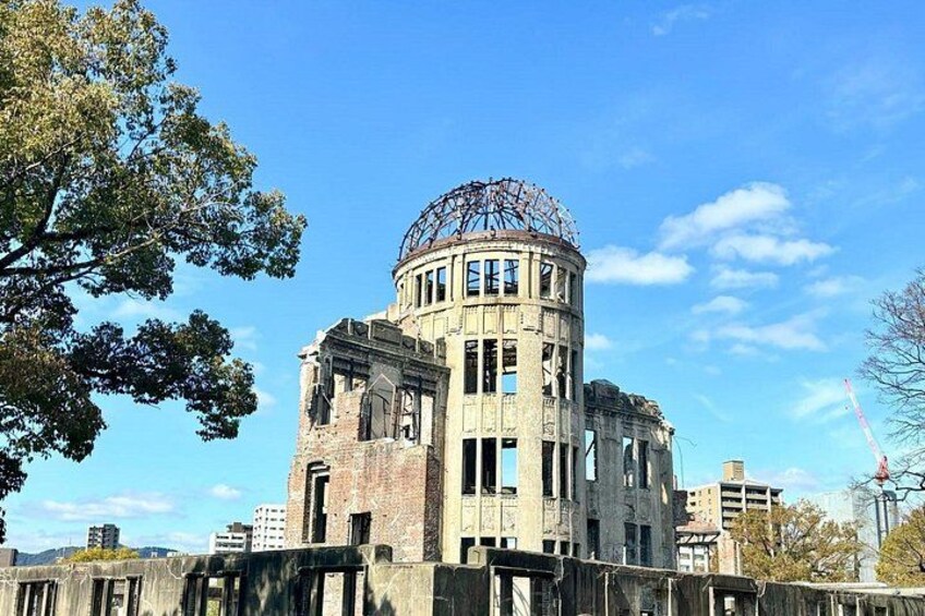 A historic building with a dome and circular structure, surrounded by trees and modern buildings. 1