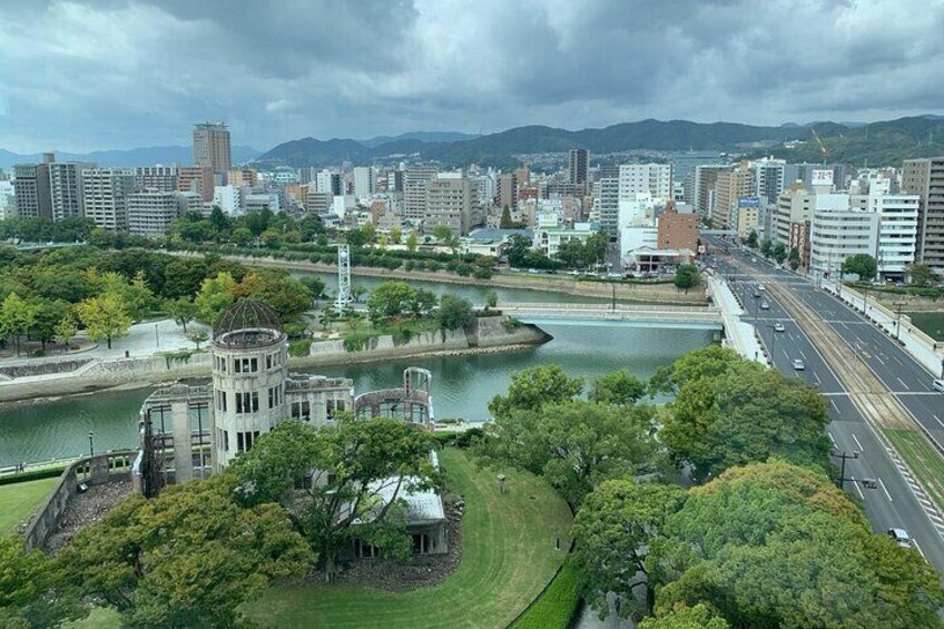 A cityscape with a river, a bridge, and a park with trees and a historic building. 2