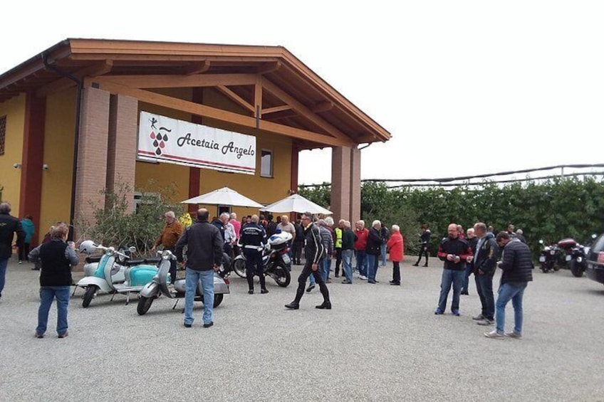 A building with a sign reading 'Acetaia Angelo' and people gathered outside. 5