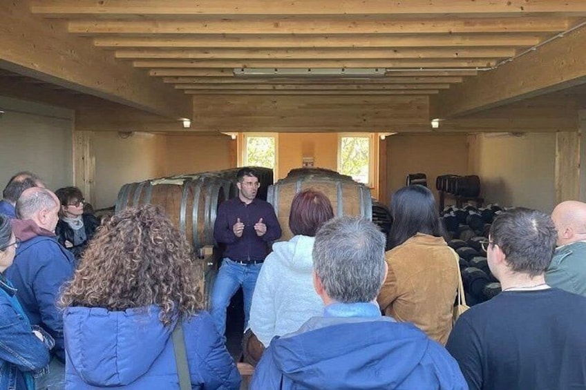 A group of people inside a wooden building with barrels. 3