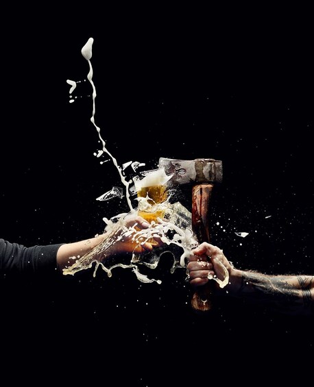 A hand holding a glass of beer with a hammer smashing it. 5