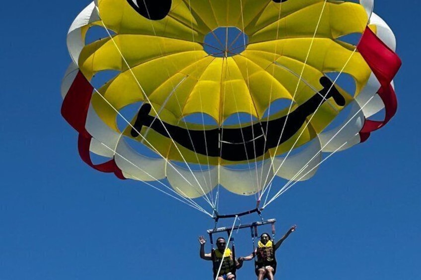 A parachute with a yellow and red design, held by two people. 5