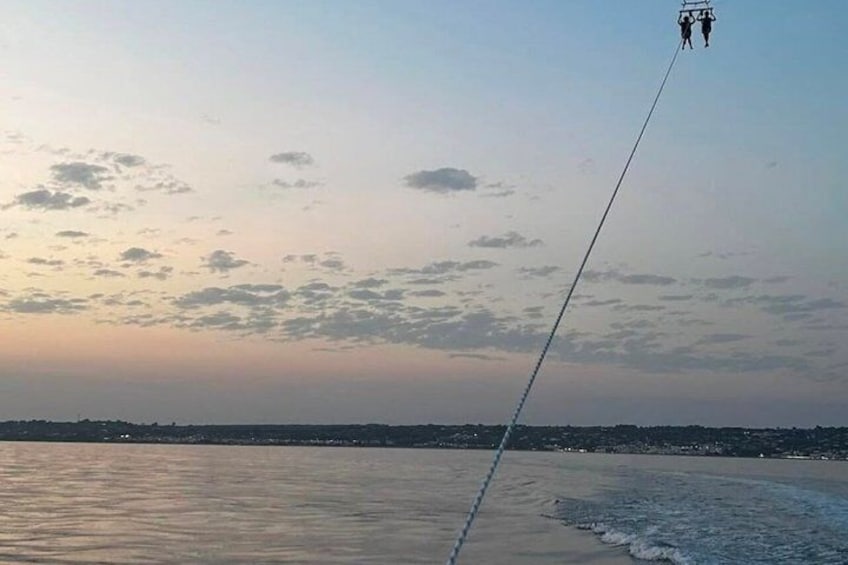 A cable car moving over a body of water during sunset. 3