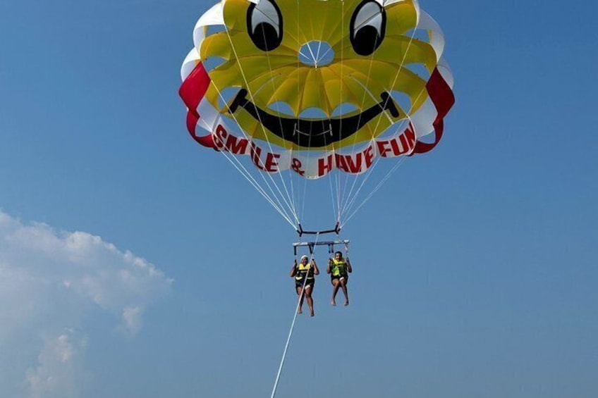A parachute with a smiley face design and the words 'SMILE & HAVE FUN' against a clear blue sky. 4