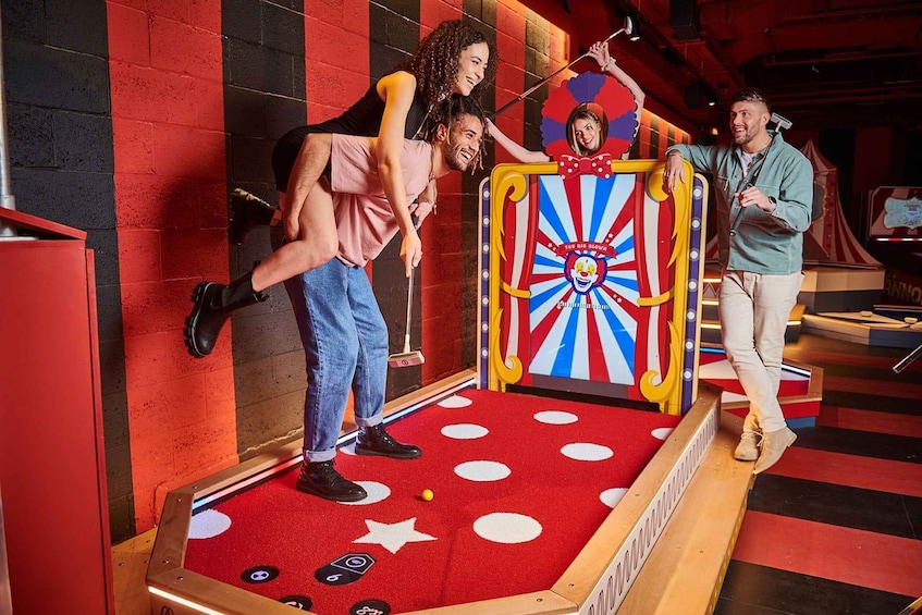 A game of darts with a dartboard and a target on a red carpet. 3