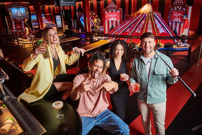 A group of people in a vibrant, themed entertainment venue with neon lights and a stage. 1
