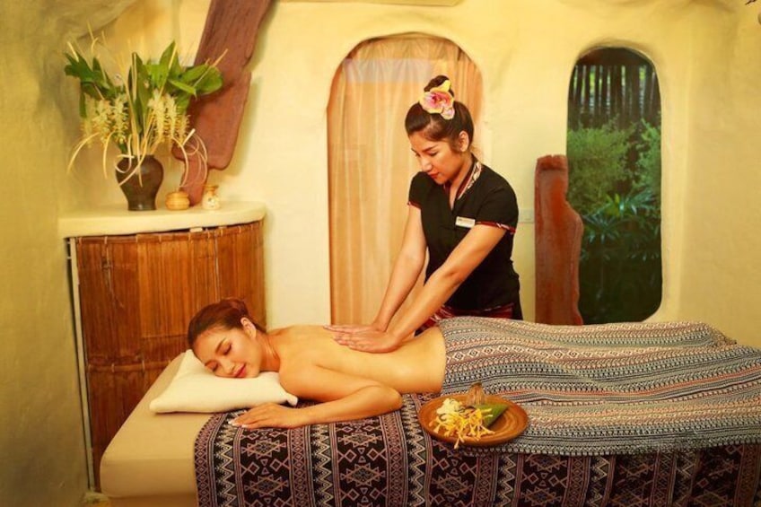 A person receiving a massage in a room with a wooden cabinet, a plant, and a window with a view of greenery. 1