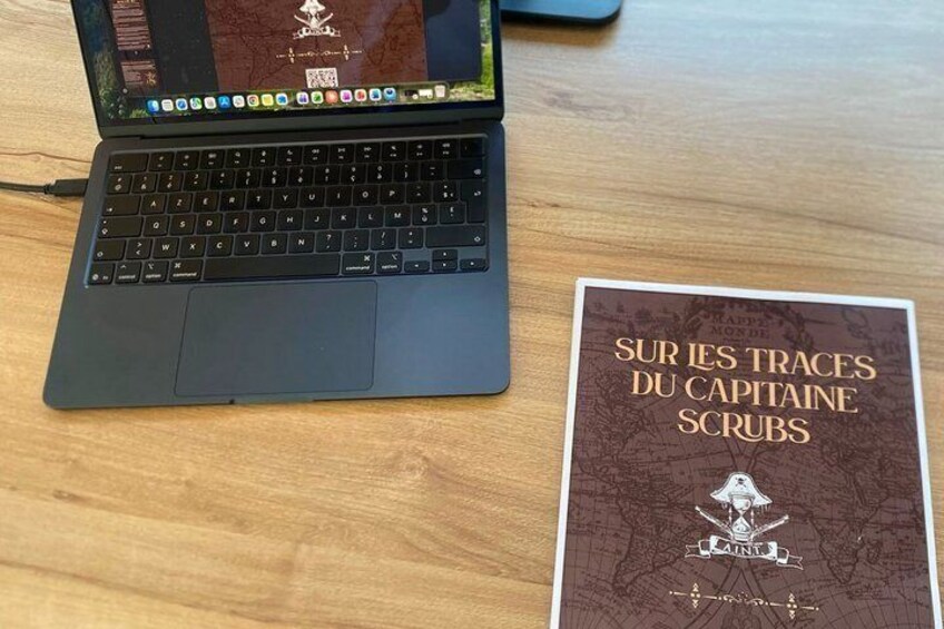 A laptop and a book titled 'Sur les traces du capitaine Scrubs' on a wooden table. 4