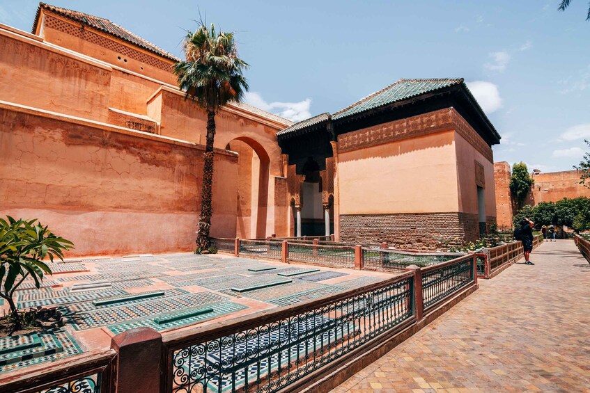 A courtyard with patterned tiles, a palm tree, and a building with a tiled roof. 1