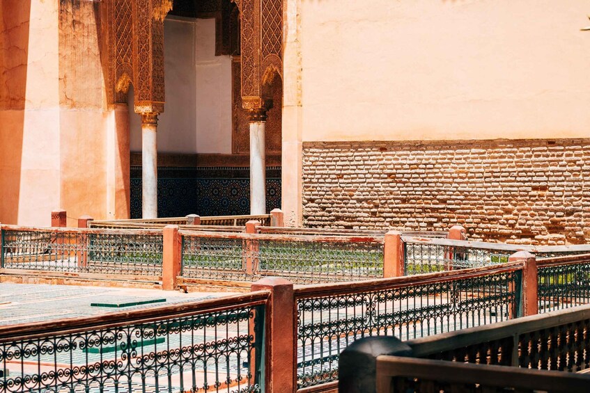 A courtyard with ornate arches, a brick wall, and a tiled floor. 4