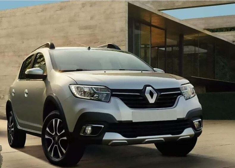 A silver Renault SUV parked in front of a modern building with large windows. 1