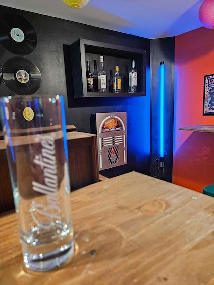 A bar with a jukebox, bottles, and vinyl records on the wall. 3