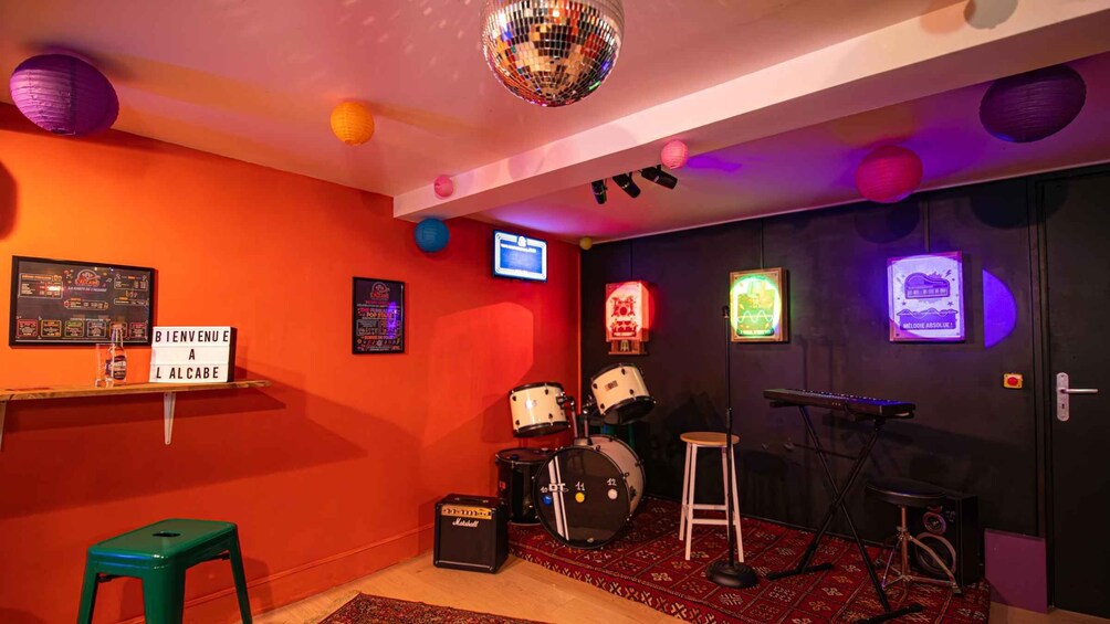 A room with a red wall, disco ball, drum set, keyboard, and various posters. 4