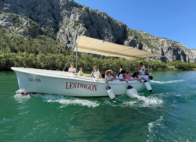 A boat named LESTRIGON with passengers enjoying a ride on clear green water. 1