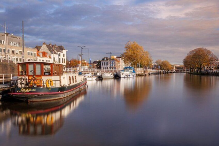 A calm river with boats, buildings, and autumn trees. 4