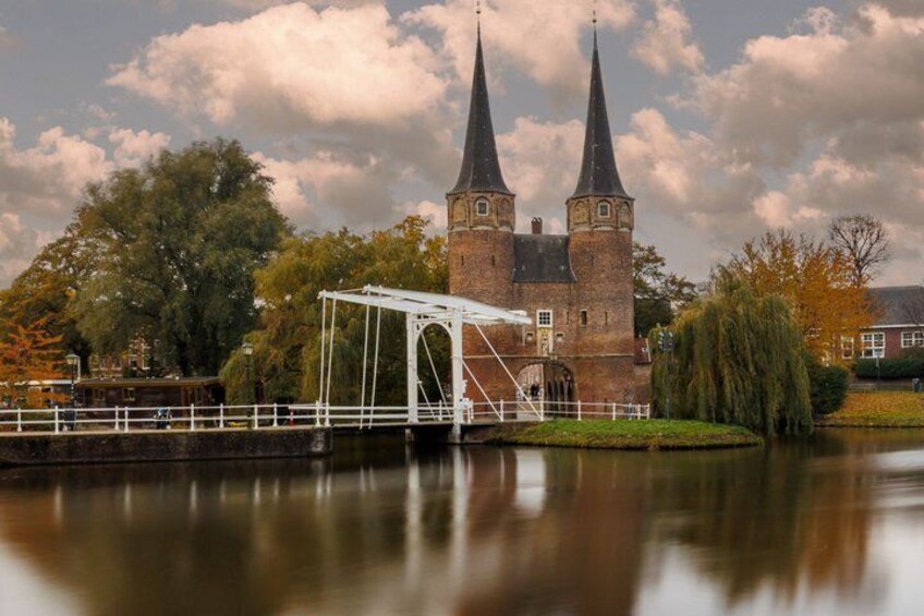 A historic castle with two tall towers, a white bridge, and a calm river reflecting the structure. 1