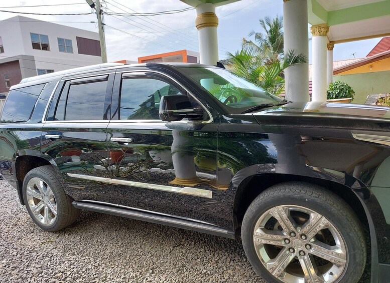 A black SUV parked on a gravel surface with a decorative planter on the side. 1