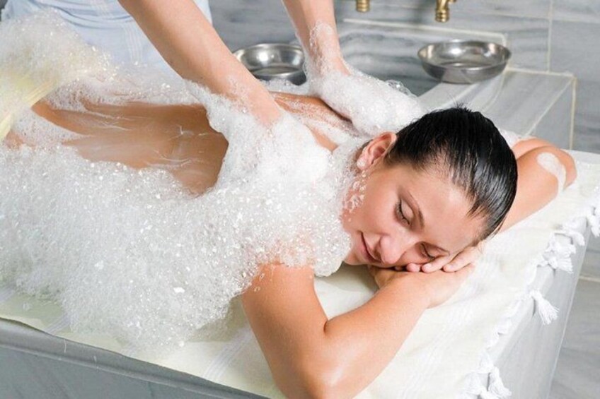 A person receiving a bubble bath treatment in a bathroom. 3