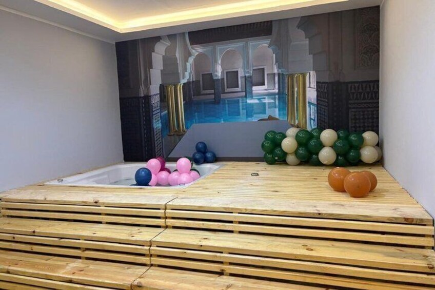 A room with a wooden platform, a pool, and balloons. 5