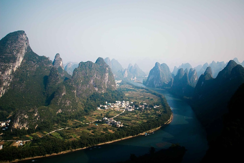 A river winding through a mountainous landscape with a small settlement along the riverbank. 2