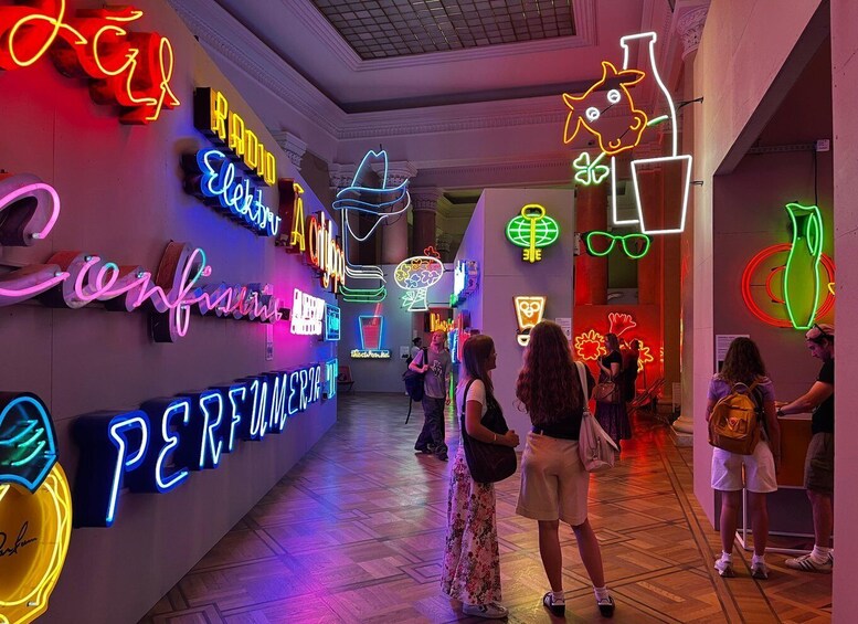 A brightly lit corridor with neon signs and a group of people walking. 1