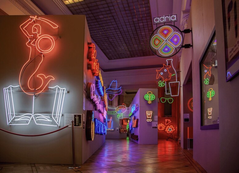 A hallway with colorful neon signs and a red rope barrier. 2