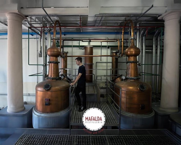 A distillery with copper stills and a person working. 1