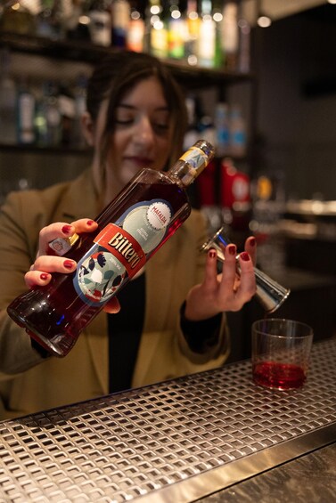 A person pouring a dark liquid from a bottle into a glass. 2