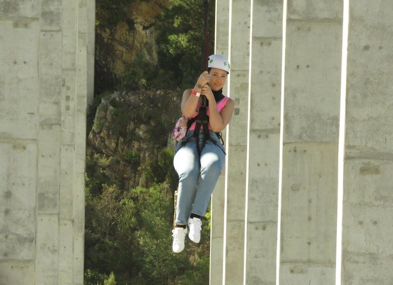 A person bungee jumping from a bridge with a rocky cliff in the background. 4