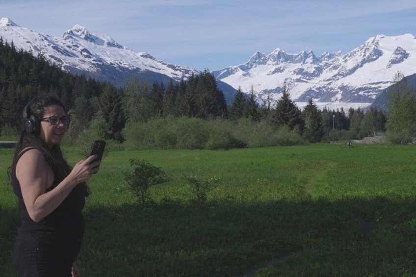 A person standing in a grassy field with snow-capped mountains in the background. 3
