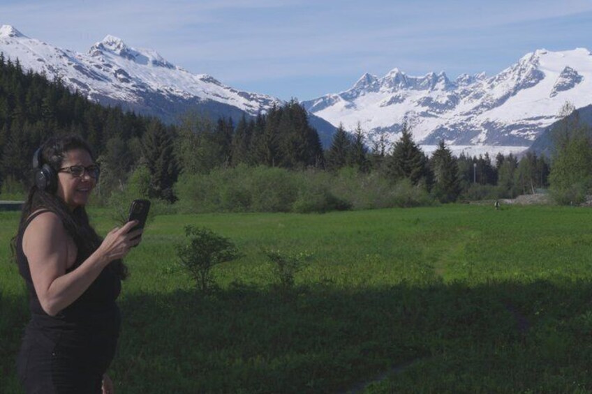 A person standing in a field with snow-capped mountains in the background. 4
