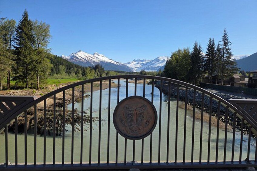 A river with a metal gate, snow-capped mountains, and trees in the background. 2