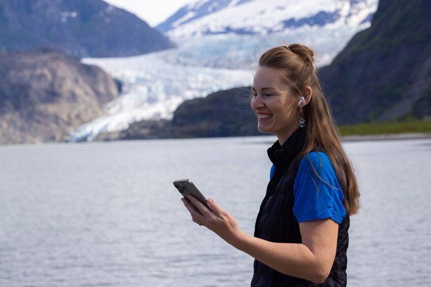 A person standing by a glacier with a smartphone. 4
