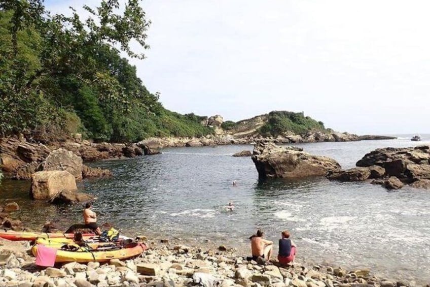 A rocky shoreline with kayaks and people near the water. 3