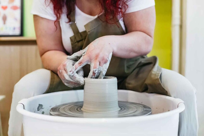A person shaping a clay pot on a pottery wheel. 1
