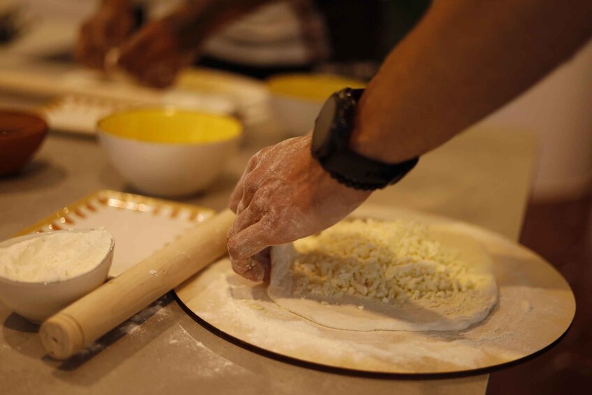 A person rolling out dough on a surface with a rolling pin and bowls of ingredients nearby. 5
