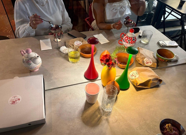 A table with various items including a laptop, colorful vases, a teapot, and food containers. 5