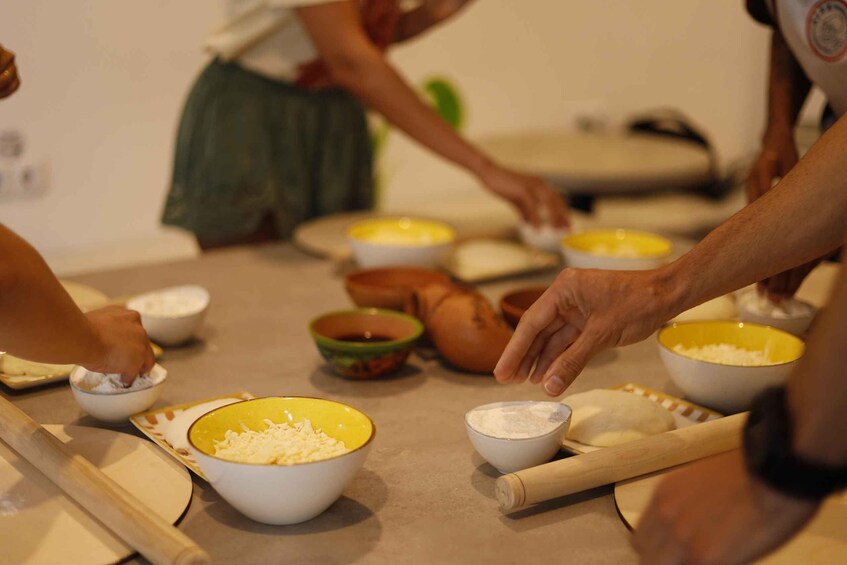 People preparing food, with bowls of ingredients and a rolling pin on the table. 1
