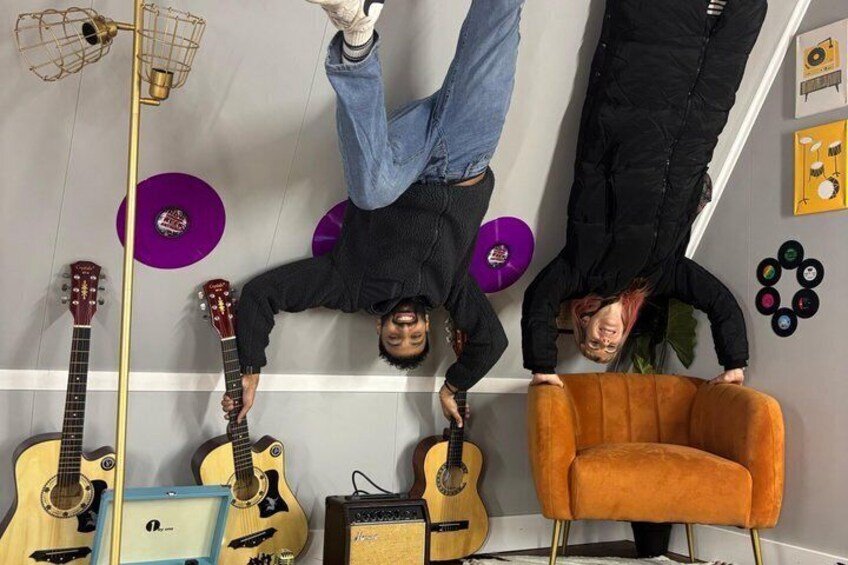 Three people hanging upside down in a room with guitars and a record player. 5