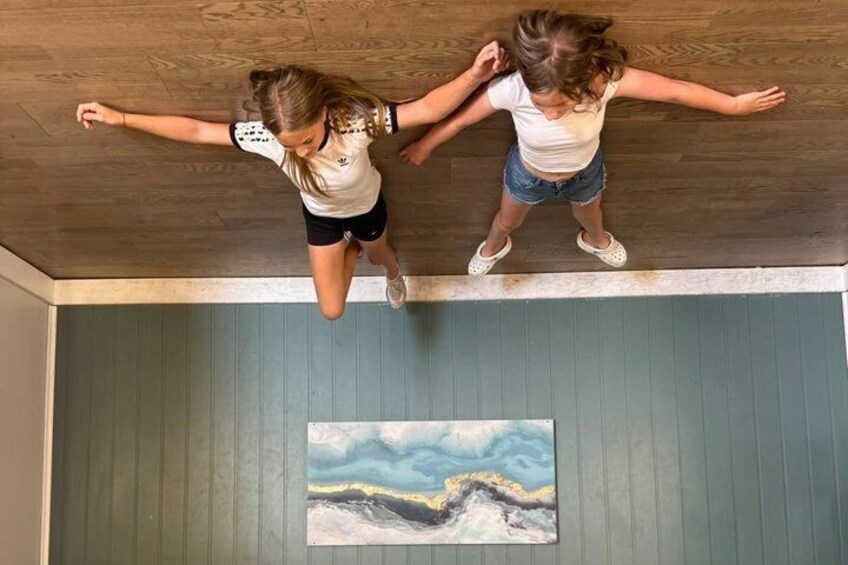 Two people jumping in a room with a wooden ceiling and a painting on the wall. 3