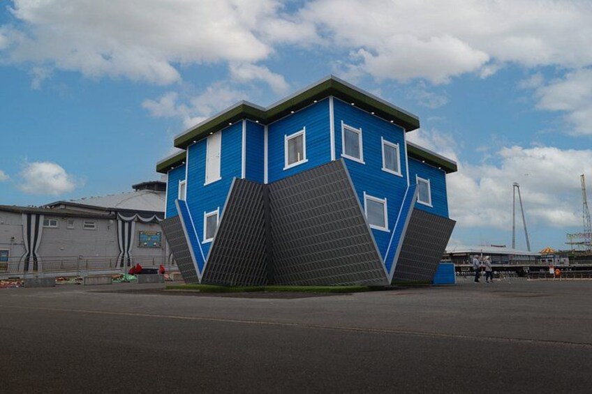 A blue building with a unique sloped roof design, located in an industrial area with a clear sky. 1