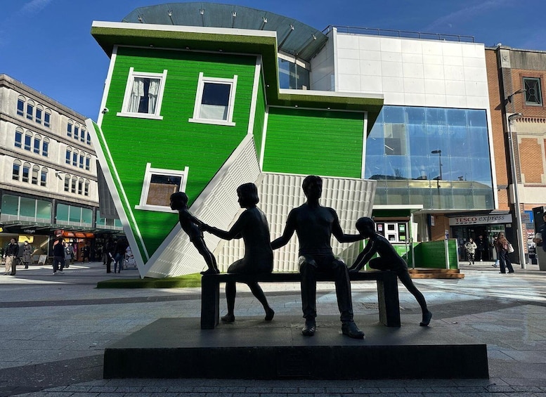 A modern building with a green facade and a sculpture of three figures. 1