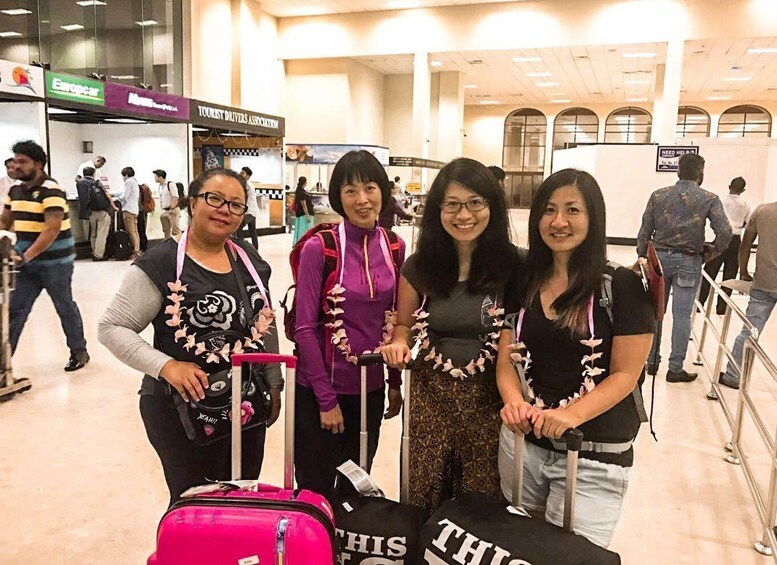 A group of people at an airport, some with luggage, standing near a sign that reads "THIS IS". 4