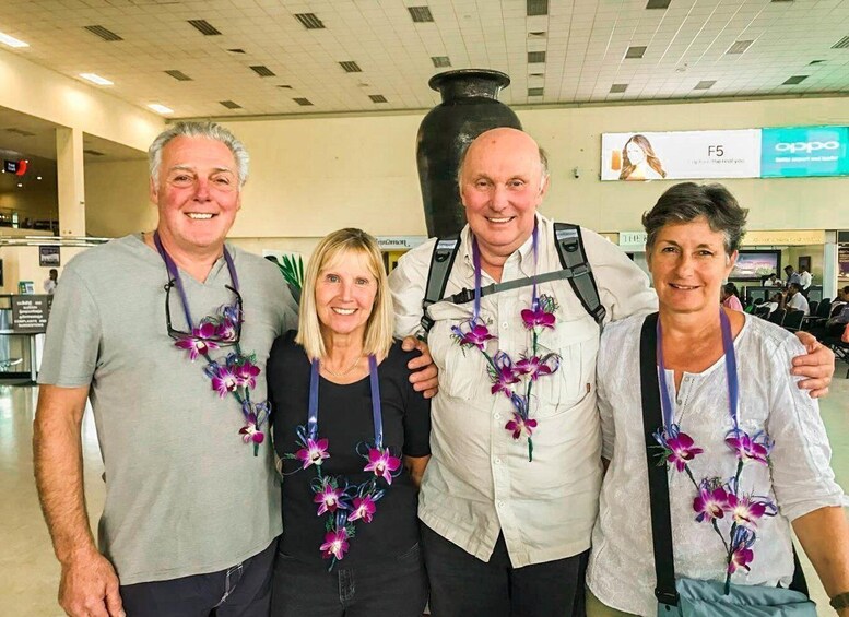 Four people in an airport with a large vase and an Oppo advertisement in the background. 3