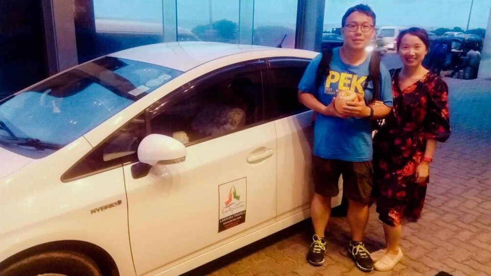 A white car with a sticker on the side and a person holding a camera. 1