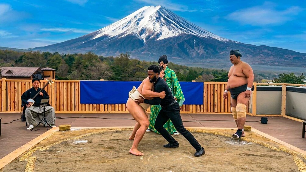 A sumo wrestling match on a wooden deck with a snowy mountain in the background. 4