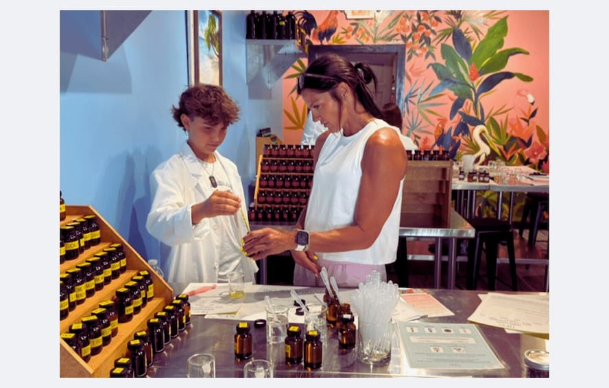 Two people in a laboratory setting with various bottles and equipment on a table. 3