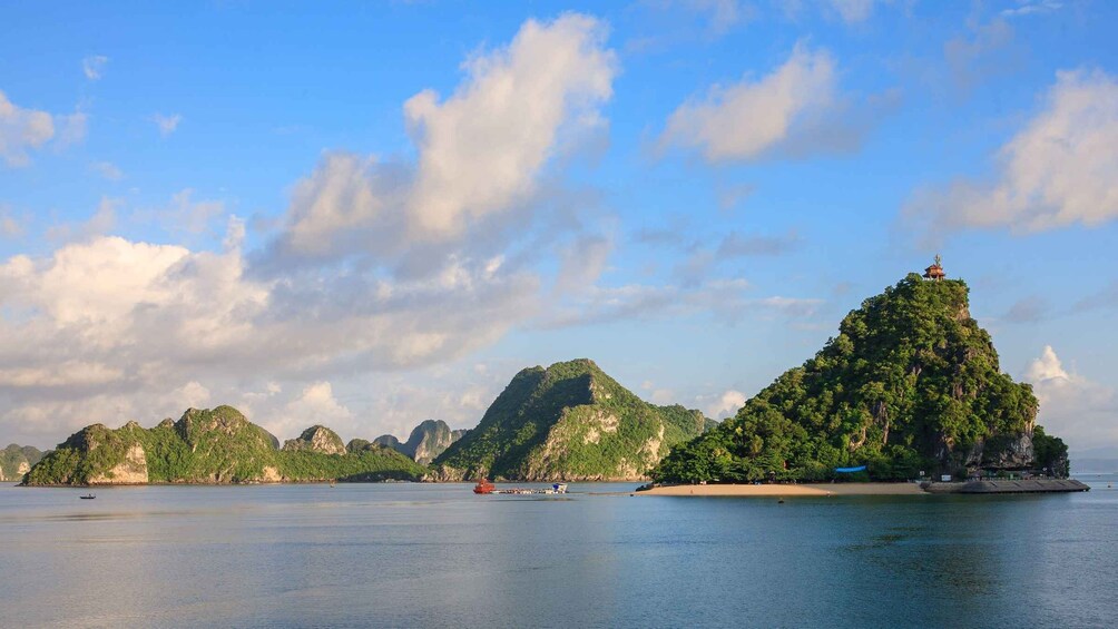 A coastal landscape with a prominent hill topped with a temple, surrounded by smaller hills and a calm sea. 4